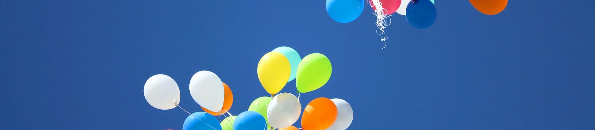 Multicoloured balloons against a blue sky, seen from below